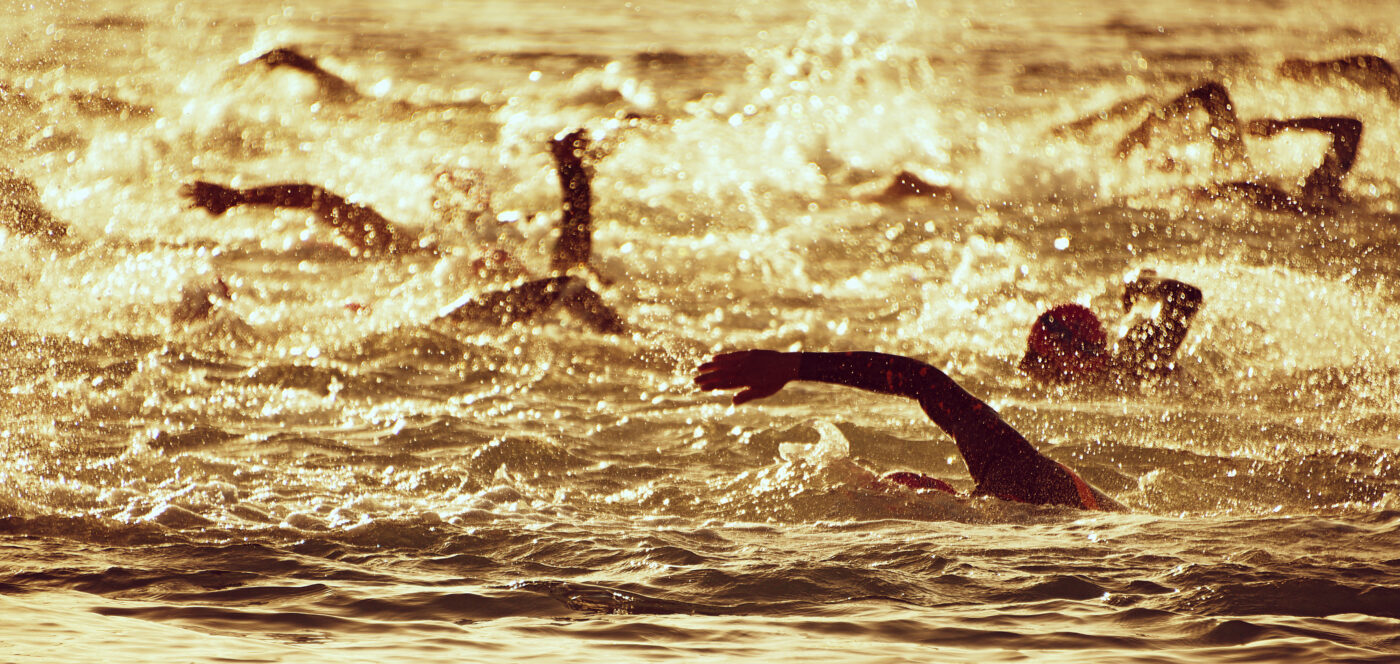 Silhoutten von Schwimmern beim Start eines Triathlons